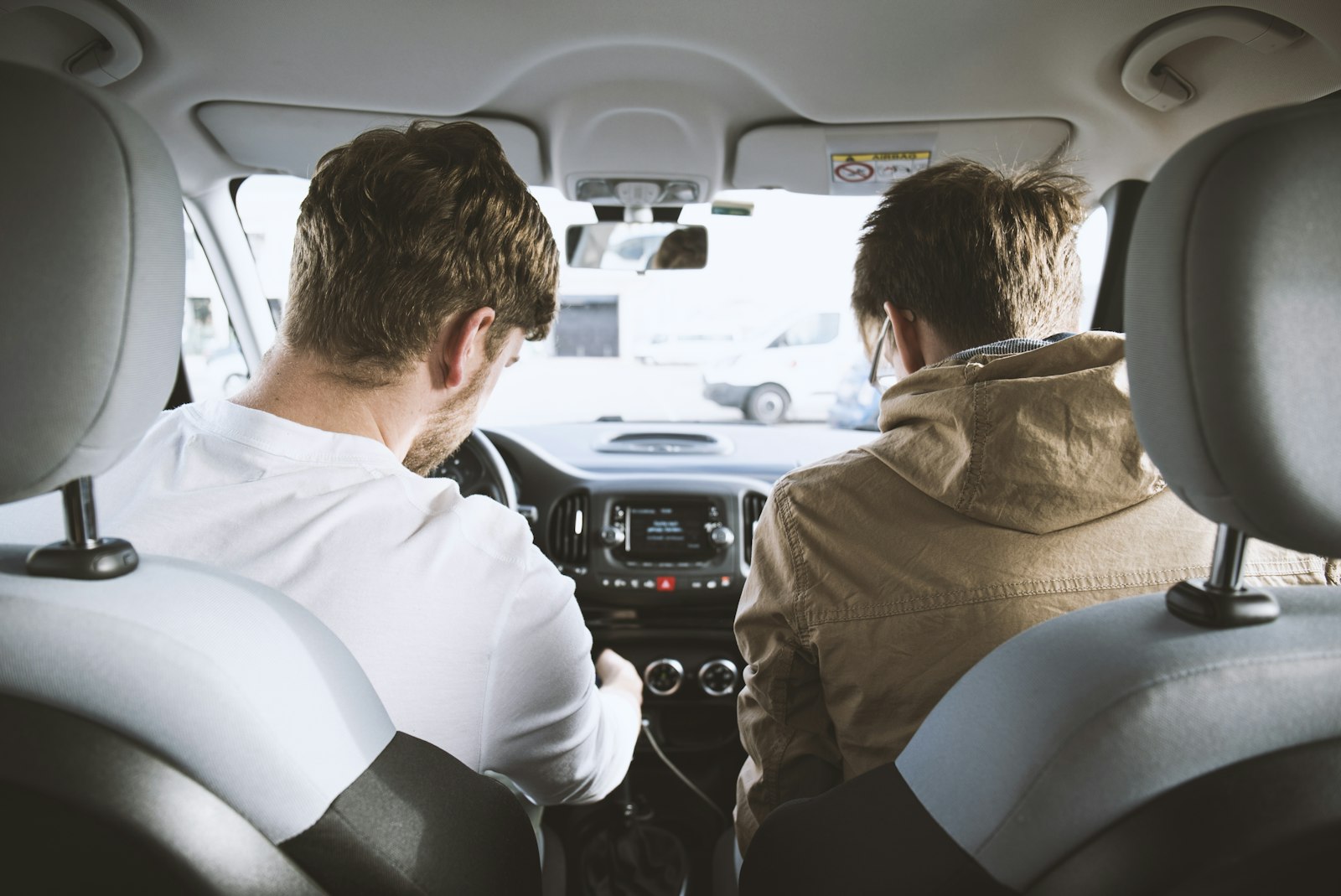 Driving instructor in the passenger seat guiding a student behind the wheel