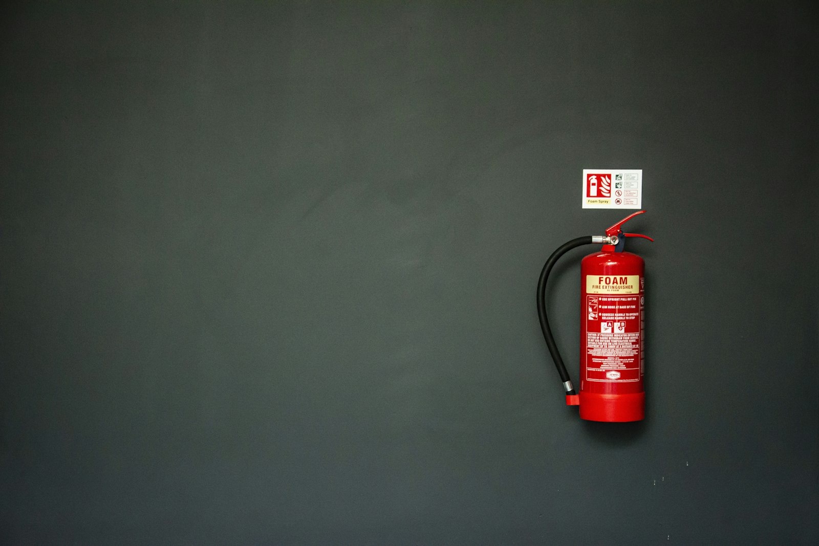 Wall-mounted fire extinguisher with its inspection signage beside it