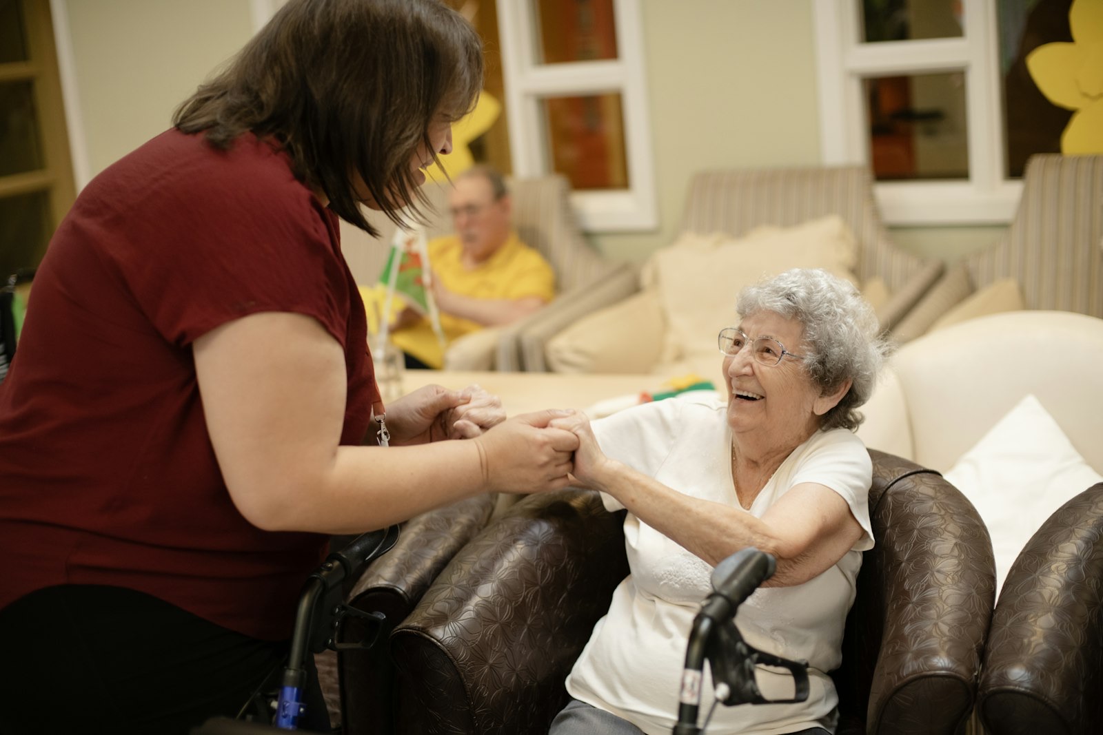 Caregiver holding hands with a smiling elderly woman using a walker