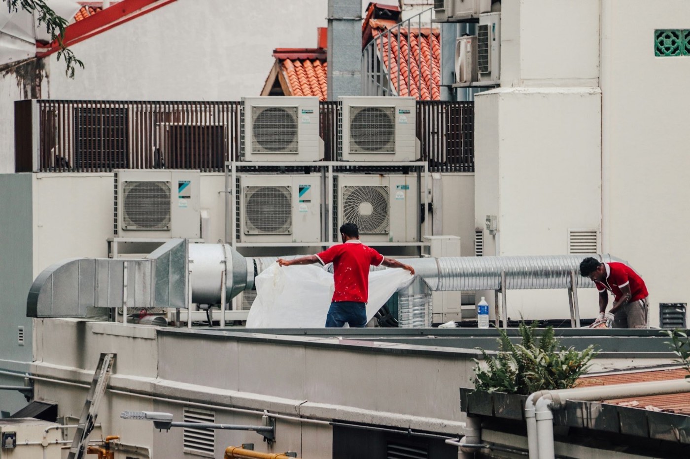 HVAC technicians servicing rooftop air-conditioning units and ductwork