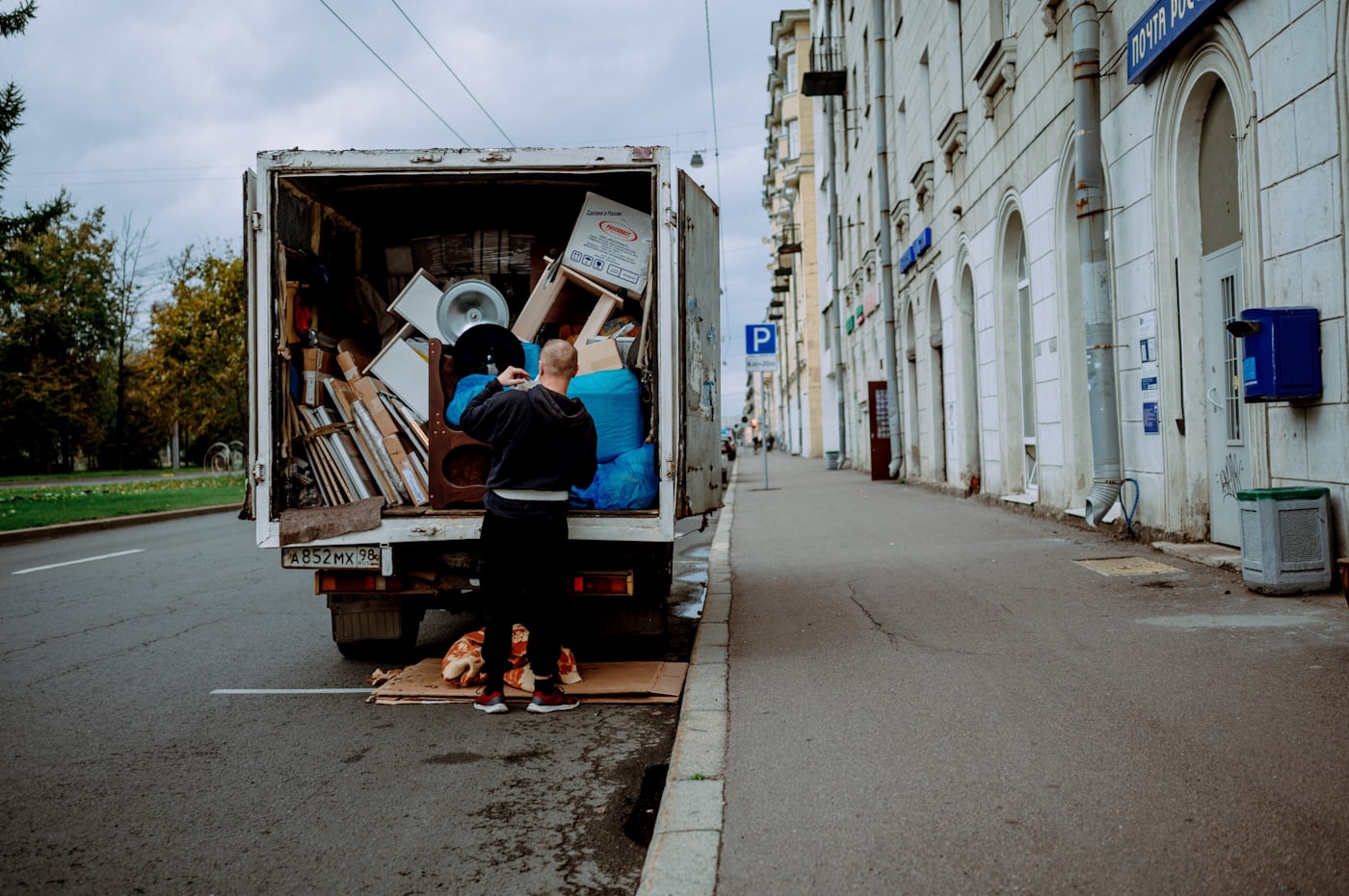Crew member loading furniture and boxes into the open back of a junk removal truck