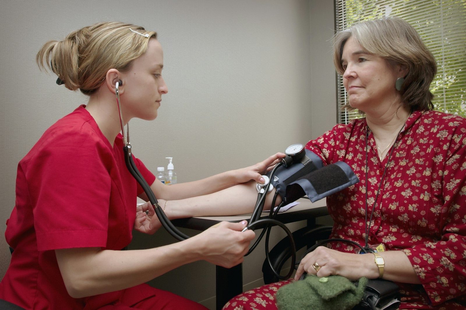 Nurse taking an older woman's blood pressure during a home visit