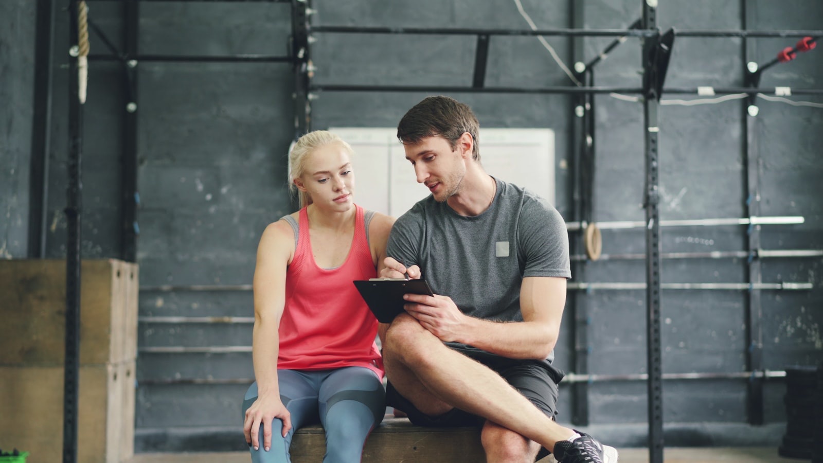 Personal trainer reviewing a workout plan on a clipboard with a client in the gym