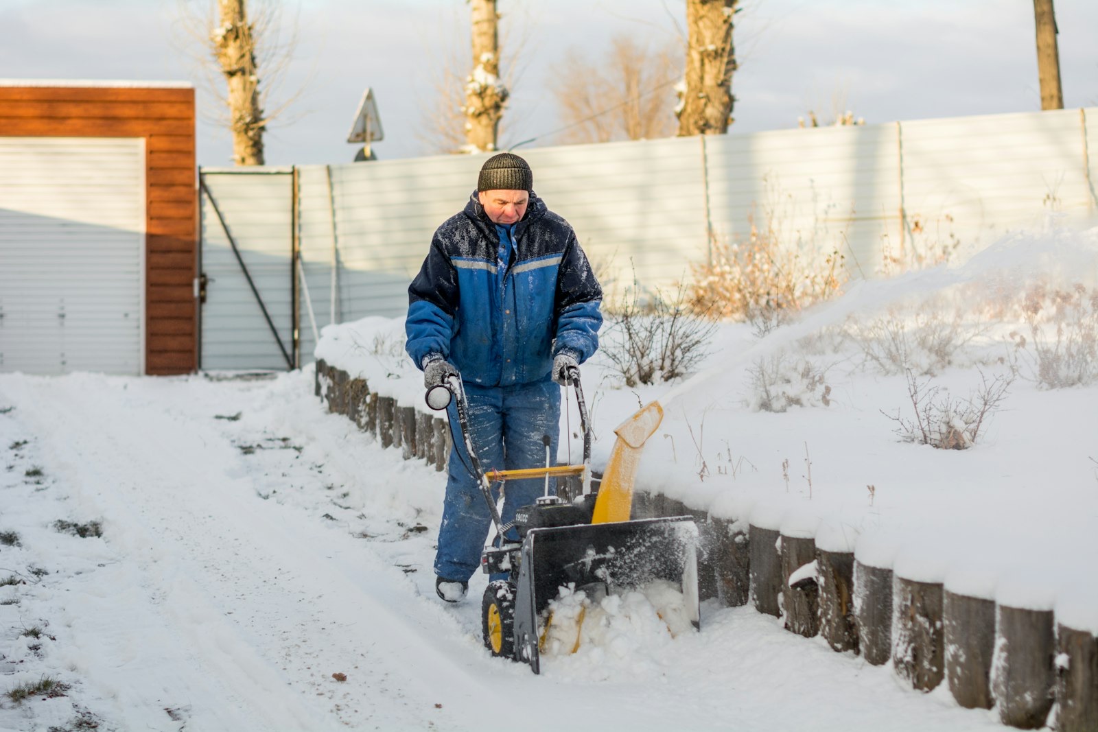 Operator clearing a snow-covered driveway with a snow blower