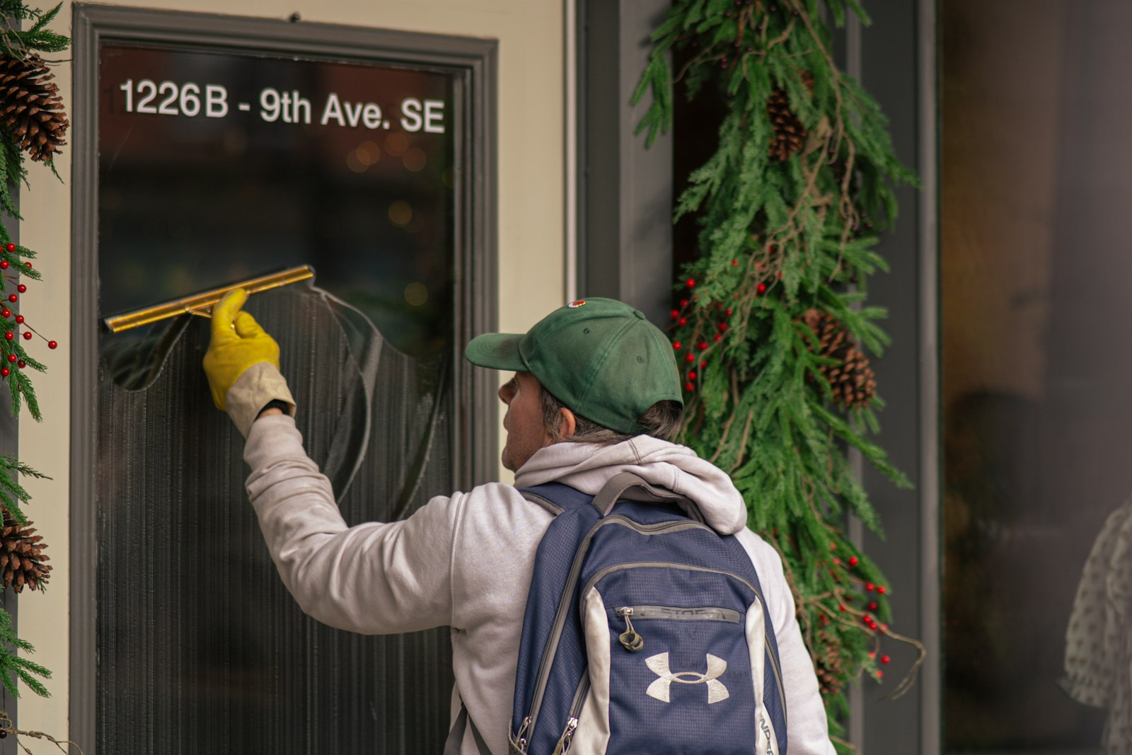 Window cleaner drawing a squeegee across a storefront door's glass